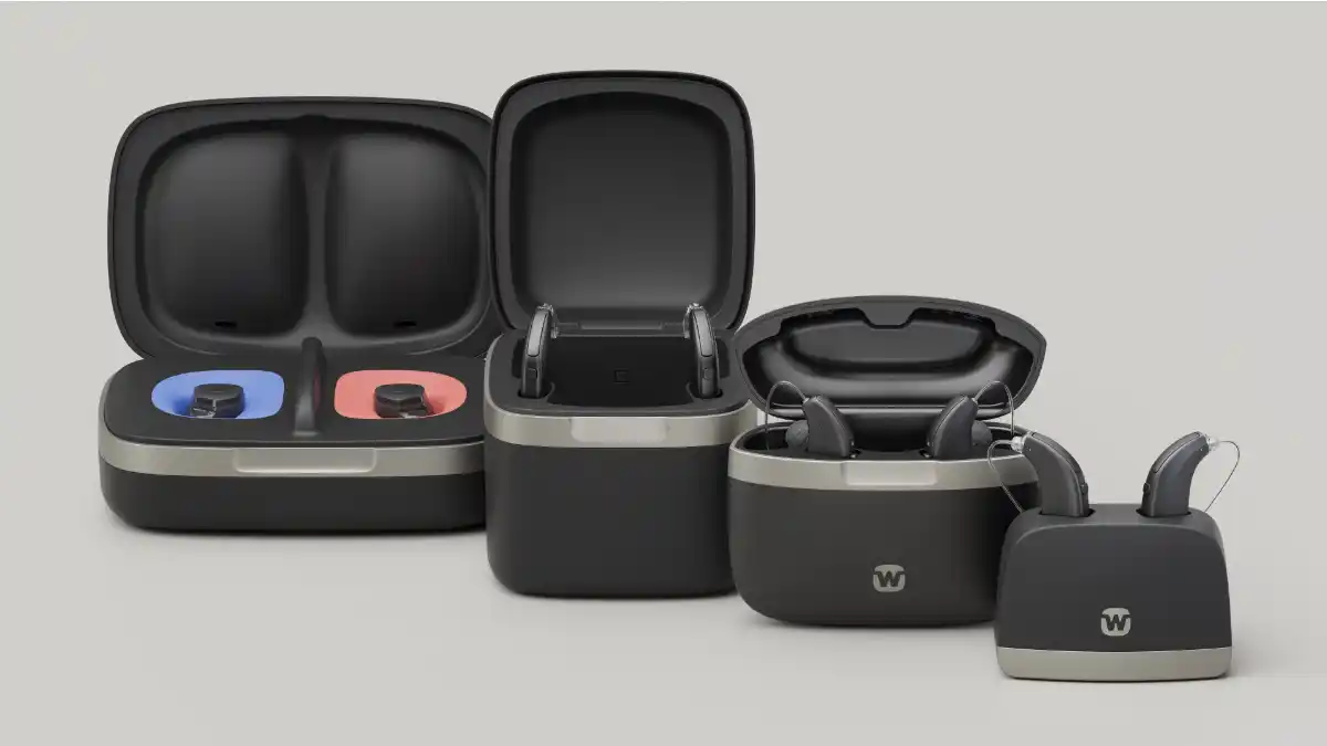 Four black and grey hearing aid chargers for different styles