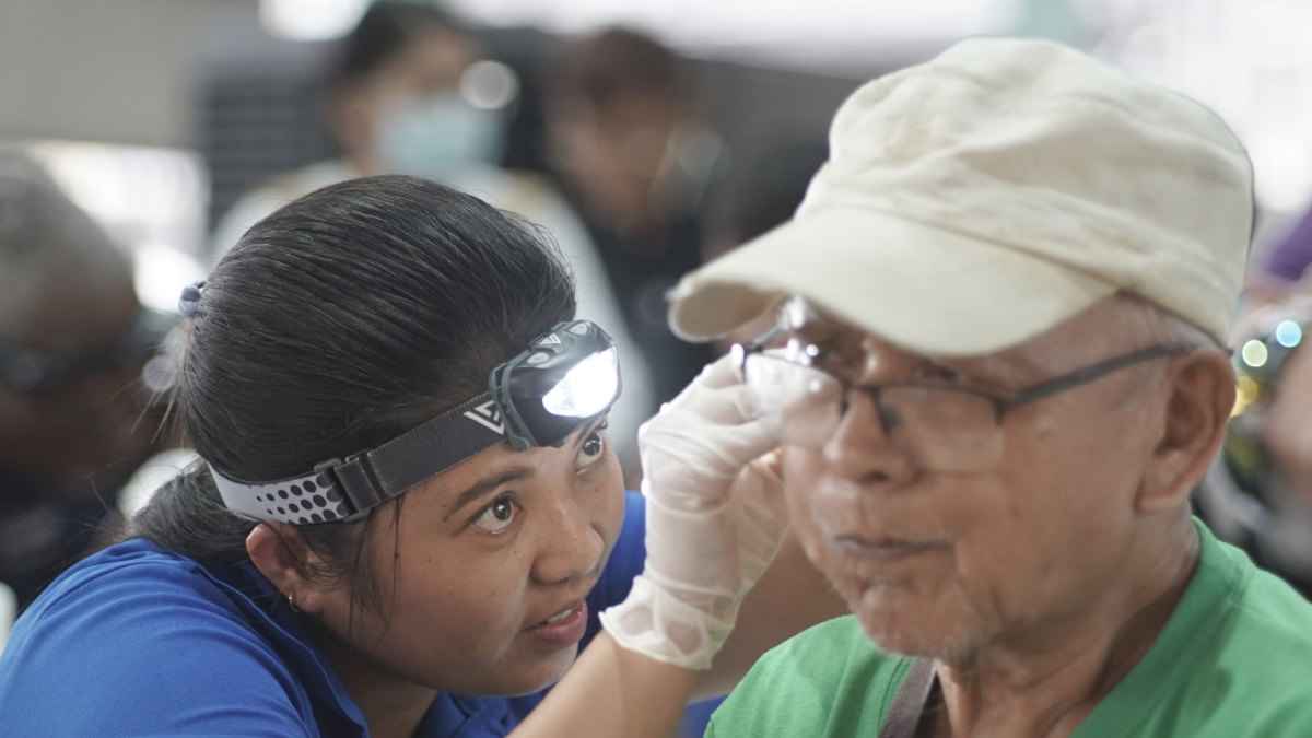 A man gets his ear cleaned by a graduate of the Starkey Hearing Institute program.