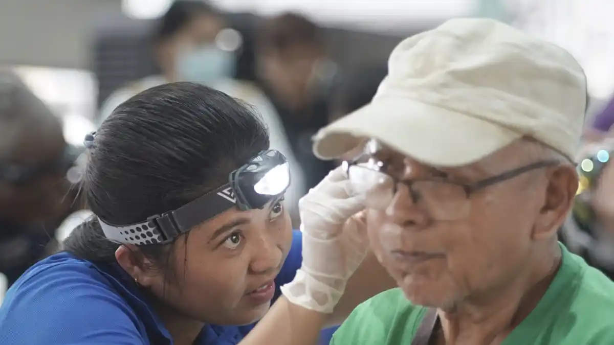 A man gets his ear cleaned by a graduate of the Starkey Hearing Institute program.
