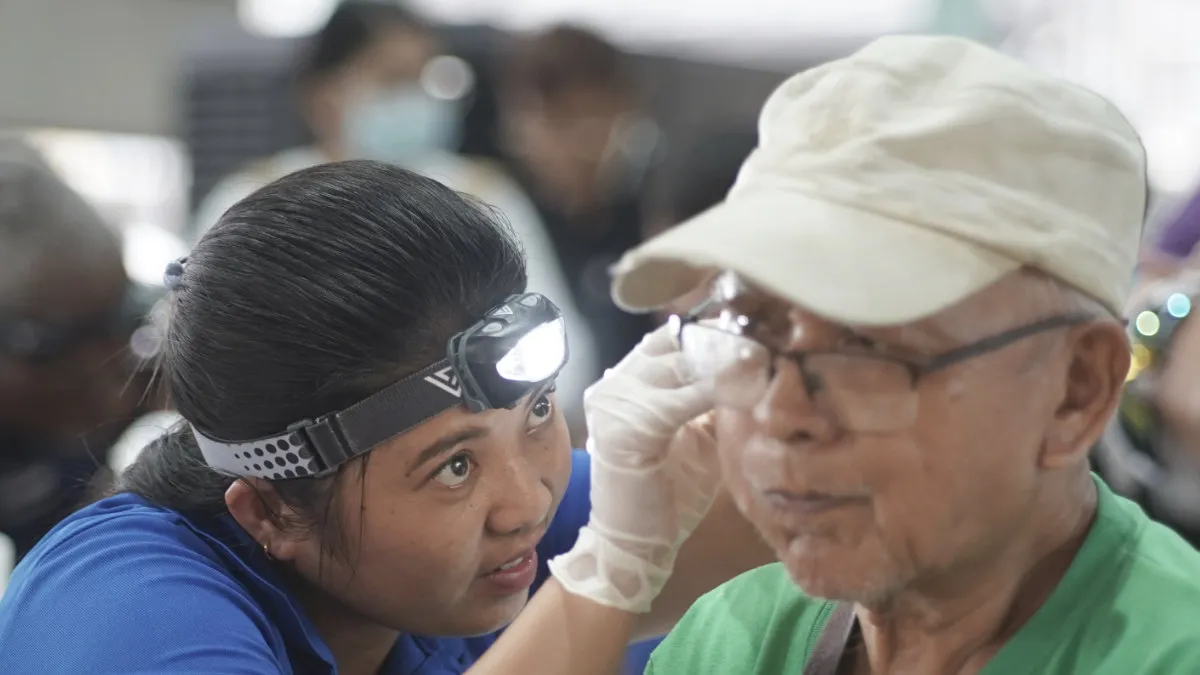 A man gets his ear cleaned by a graduate of the Starkey Hearing Institute program.