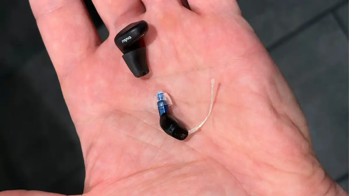 Comparison of two instant-fit in-ear rechargeable wireless hearing aids shown in my hand: Signia Active Mini IX compared with Oticon Zeal.
