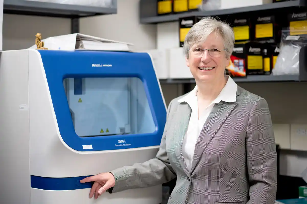 Terry-Lynn Young stands next to a Genetic Analyzer. Photo courtesy Richard Blenkinsopp.