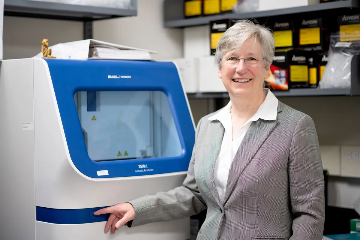 Terry-Lynn Young steht neben einem Genetic Analyzer. Foto mit freundlicher Genehmigung von Richard Blenkinsopp.