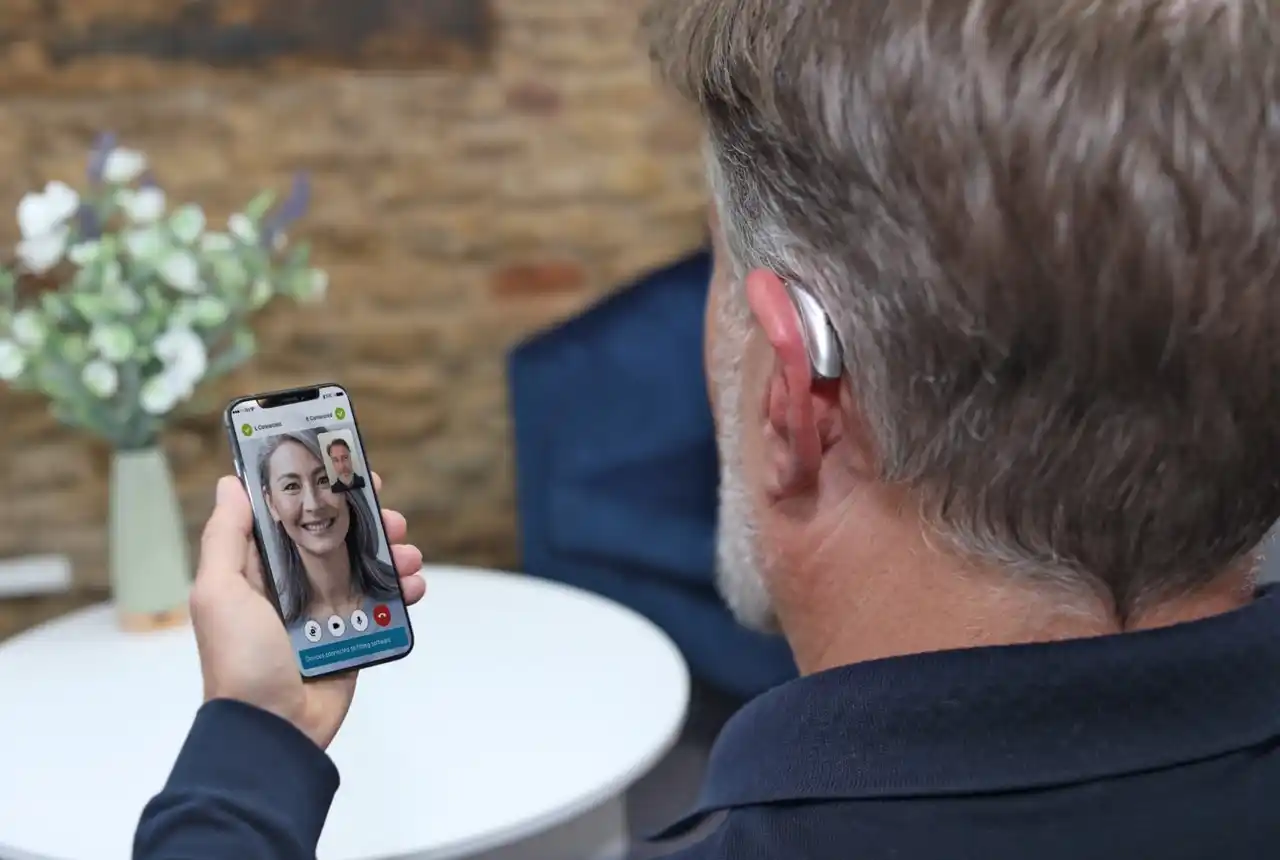 Man talking with audiologist via myPhonak app