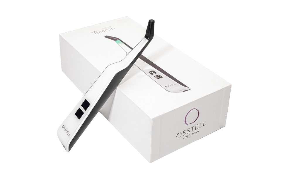 The Osstell Beacon, leaning against its packaging, in front of a white background.