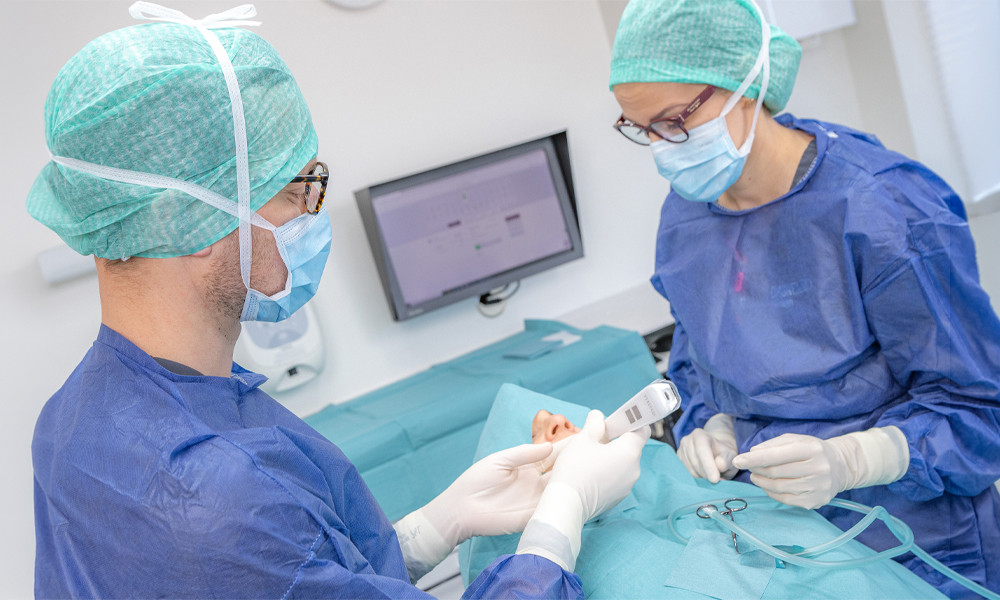 Two clinicians measuring implant stability using ISQ with the Osstell Beacon in a dental practice.
