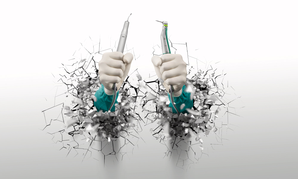 Two hands holding dental handpieces on a white background.
