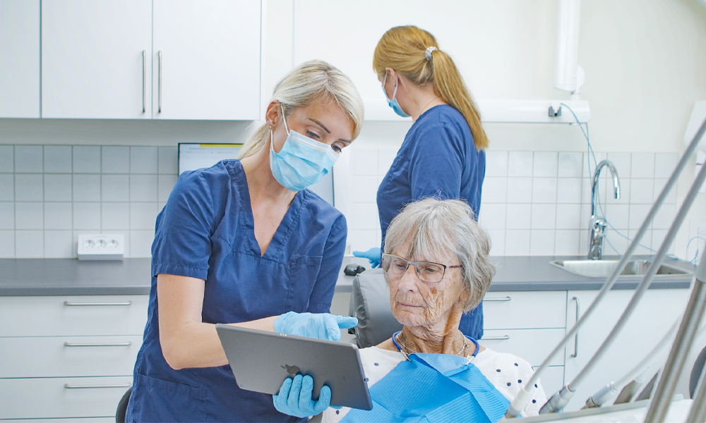 Las dentistas le muestran a una paciente la plataforma OsstellConnect en una sala de consulta.