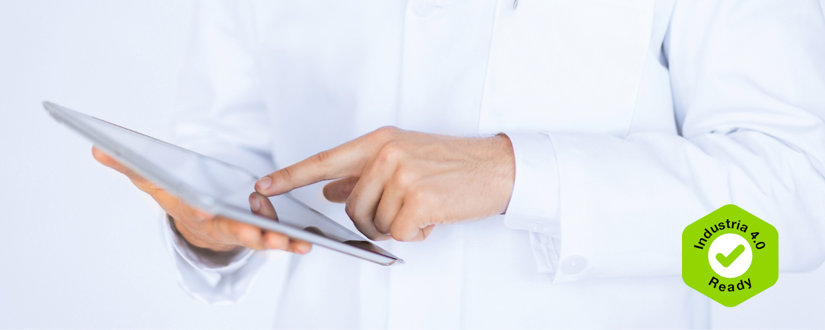 Un operatore sanitario utilizza un tablet per accedere a dati digitali e flussi di lavoro connessi, munito di un badge "Ready for l'Industria 4.0".