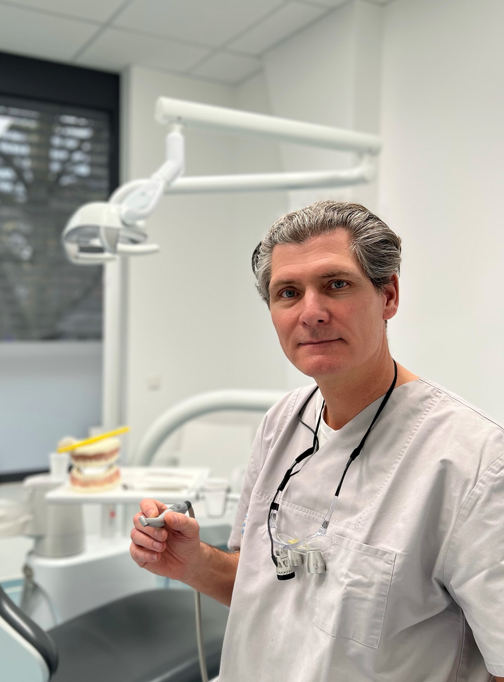 Dr. David Hagen, sosteniendo una pieza de mano contra-ángulo Synea, sonriendo a la cámara.