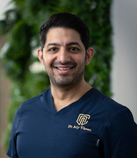 Dr Aly Virani zâmbește la cameră.