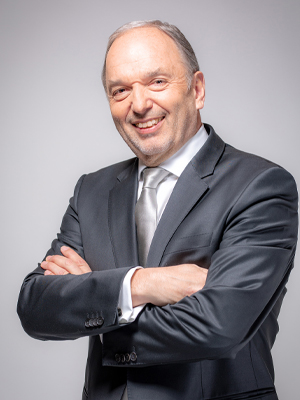 Peter Malata, Eigentümer und Geschäftsführer W&H-Gruppe lächelt in die Kamera vor einem grauen Hintergrund.