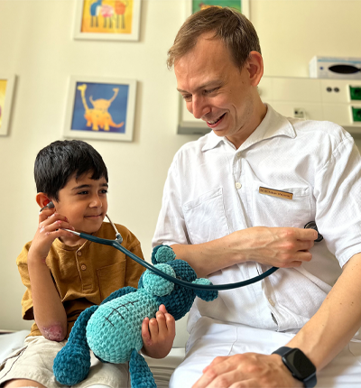 A kid with epidermolysis bullosa and an expert for medical care, smiling.
