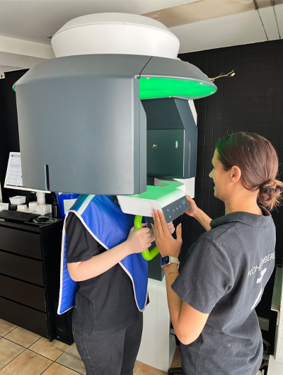 A dental assistant adjusts the Seethrough Max as the patient holds onto the handles and prepares for imaging.