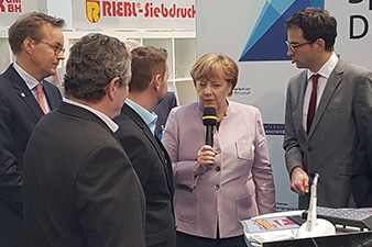 El cogerente de RIEBL-Siebdruck y la canciller Angela Merkel conversando.