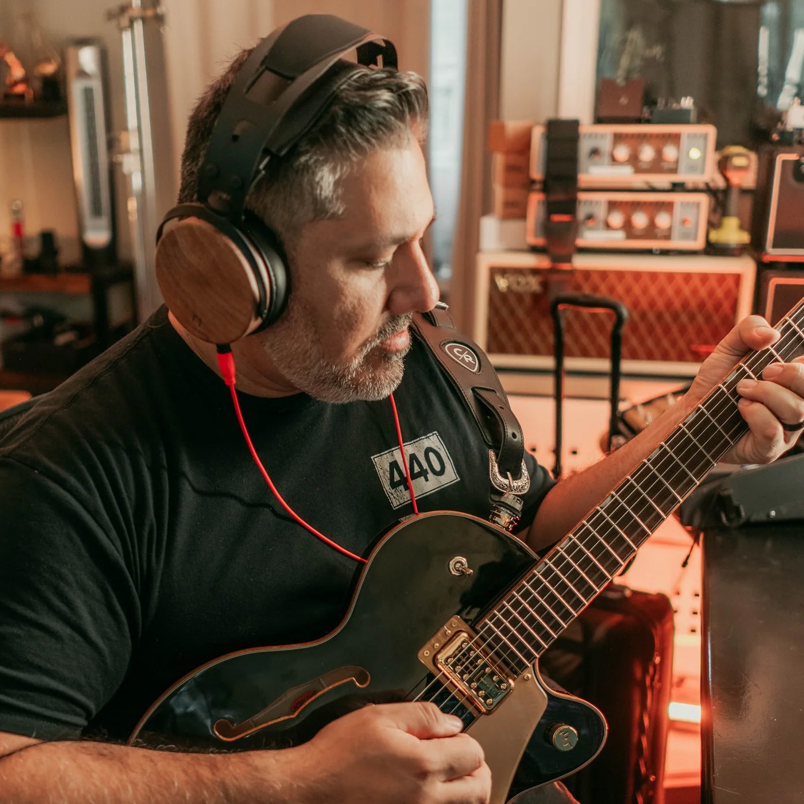 Chris Rocha nutzt die Ollo Audio R1 10 Kopfhörer und spielt Gitarre