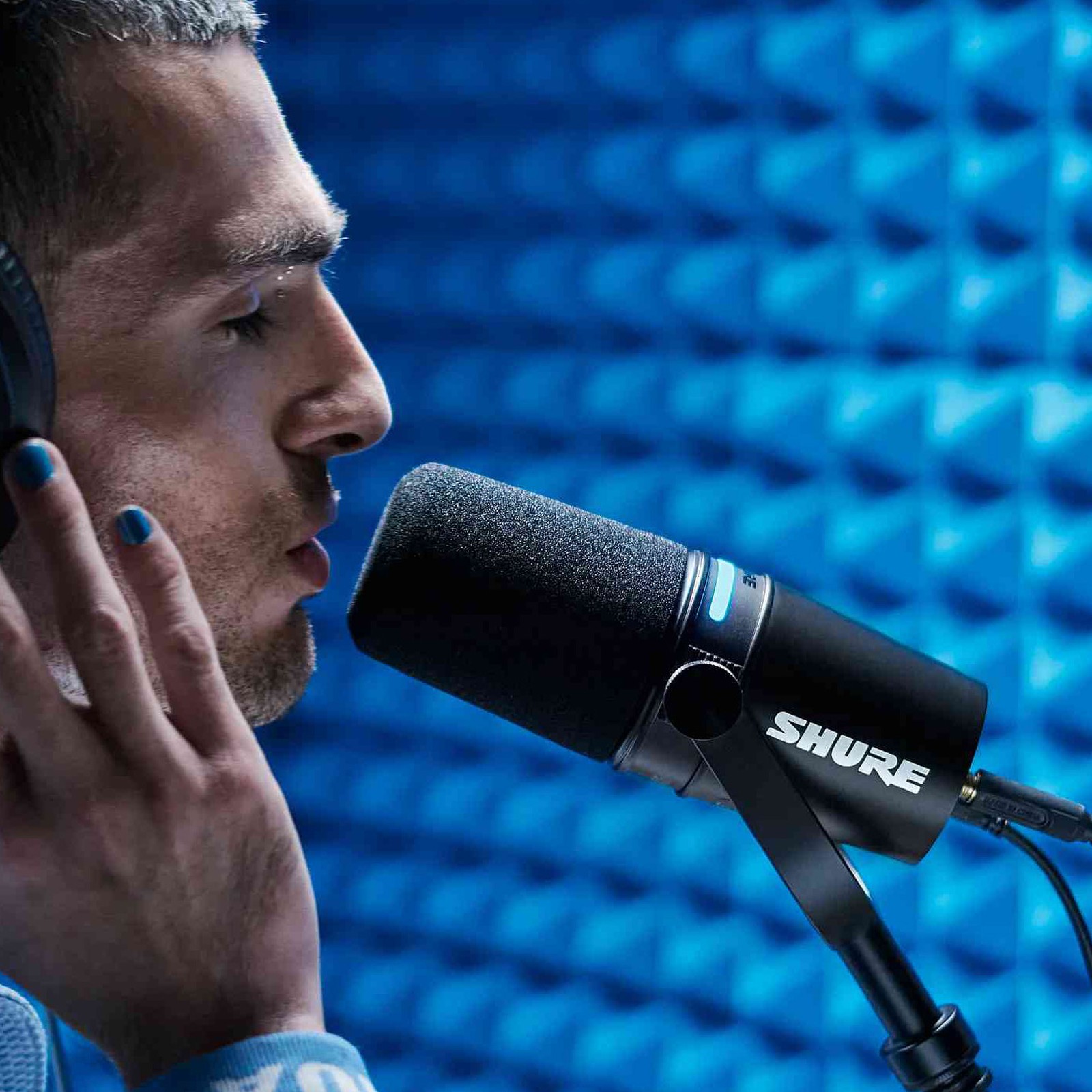 Mann singt in ein Shure MV7+ Black Broadcast Microphone