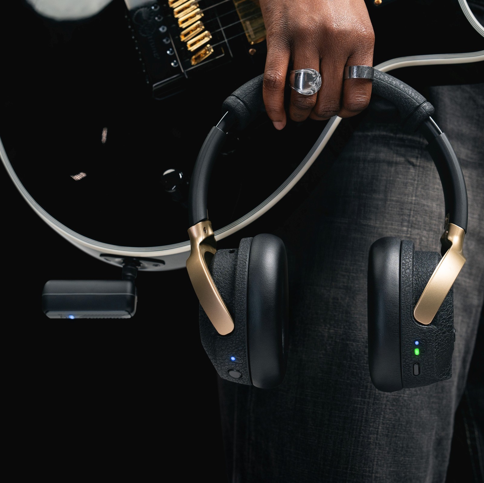 L'émetteur Positive Grid Spark Neo sur la guitare et le casque dans une main