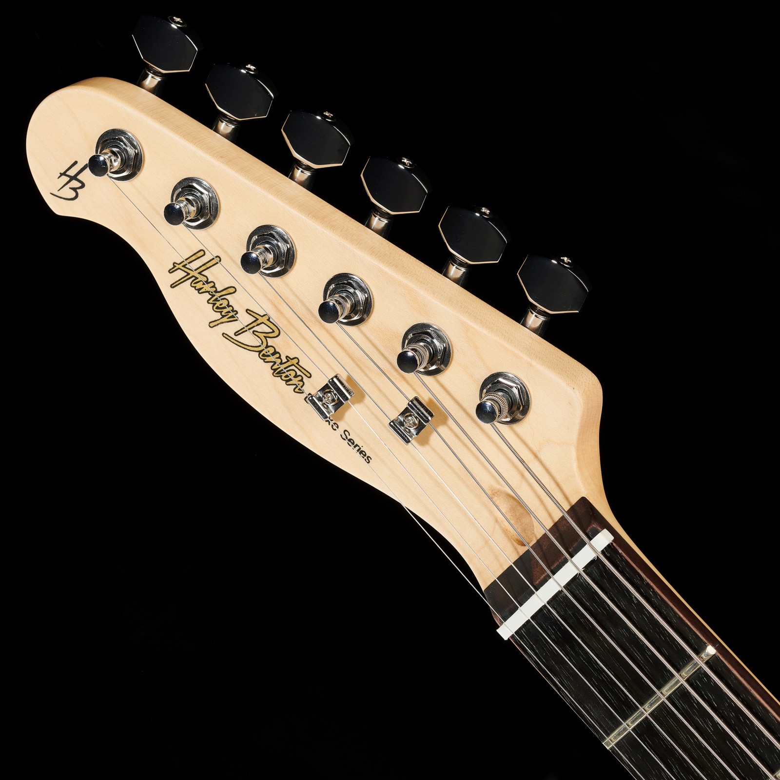 Kopfplatte mit sechs Mechaniken, zwei Saitenniederhaltern und der Aufschrift "Harley Benton Deluxe Series"