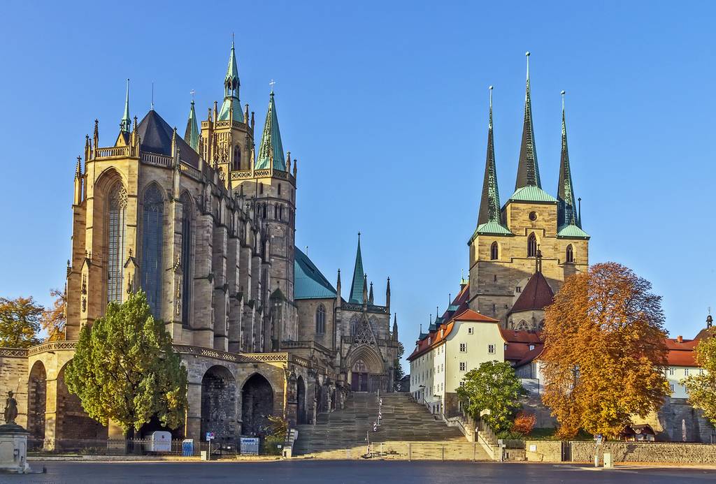 Erfurter Dom und Severikirche mit hohen Türmen, umgeben von Bäumen, unter einem klaren blauen Himmel