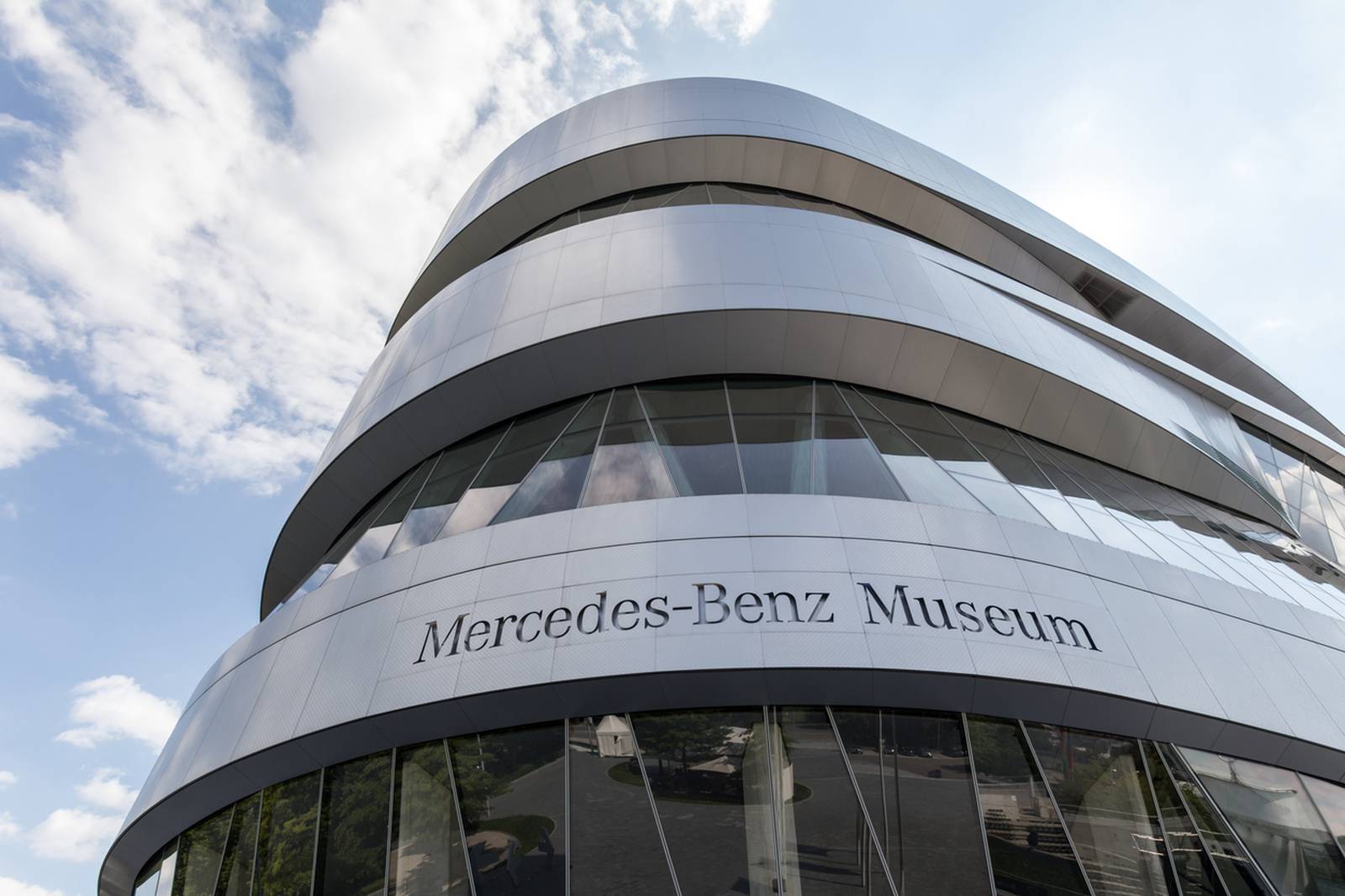 Futuristische silberne Fassade des Mercedes-Benz Museums vor blauem Himmel mit Wolken