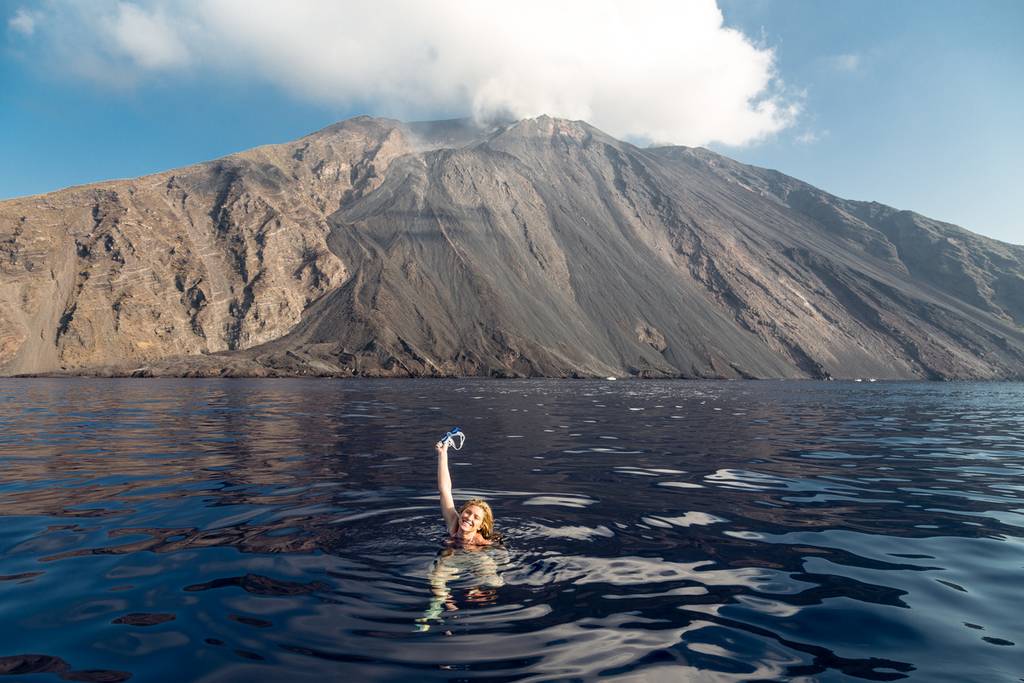 una donna fa il bagno nelle acque di fronte all'isola di Stromboli