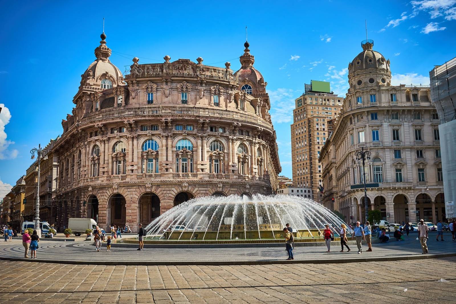 Die Piazza De Ferrari in Genua, Italien, mit einem großen zentralen Springbrunnen und historischen Gebäuden unter klarem blauen Himmel