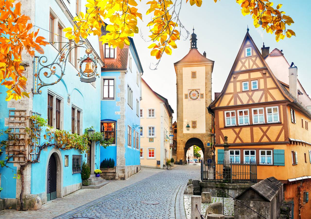 Affascinante strada acciottolata a Rothenburg ob der Tauber, Germania, con colorate case a graticcio e foglie autunnali.