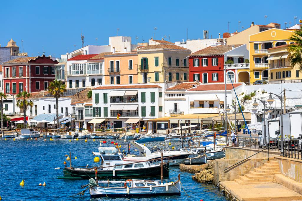 Manhon, Borgo costiero colorato con barche ormeggiate in un porto vivace, circondato da edifici di charme sotto un cielo azzurro limpido.