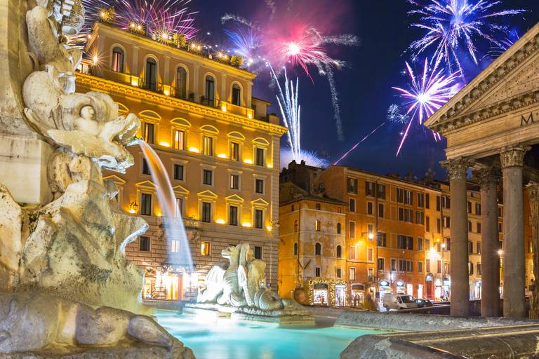 Feuerwerk erleuchtet den Nachthimmel über einem beleuchteten Brunnen und historischen Gebäuden, darunter das Pantheon, und schafft eine festliche Atmosphäre.