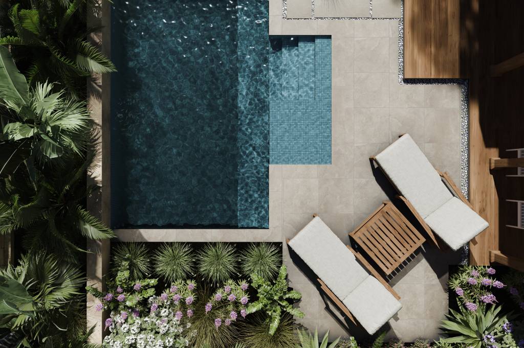 Aerial view of a small swimming pool with two sun loungers and a wooden side table, surrounded by lush greenery and vibrant flowers.
