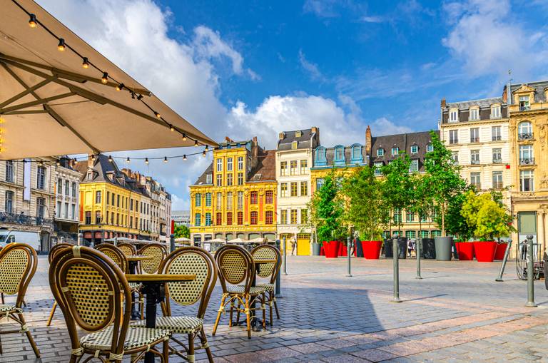 Ein sonniger Platz mit farbenfrohen historischen Gebäuden, Café-Sitzplätzen im Freien