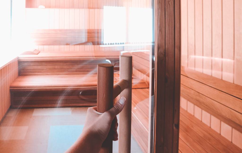 Vrouw die de deur van een sauna opent