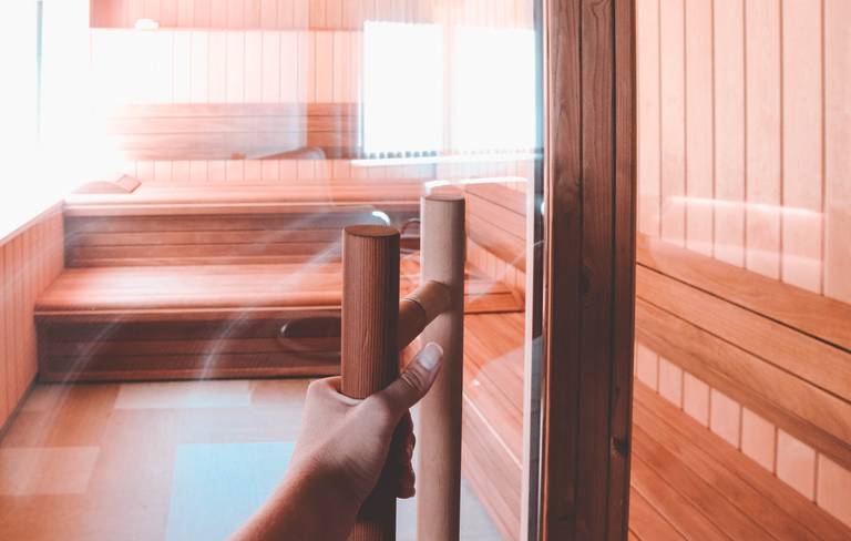 Vrouw die de deur van een sauna opent