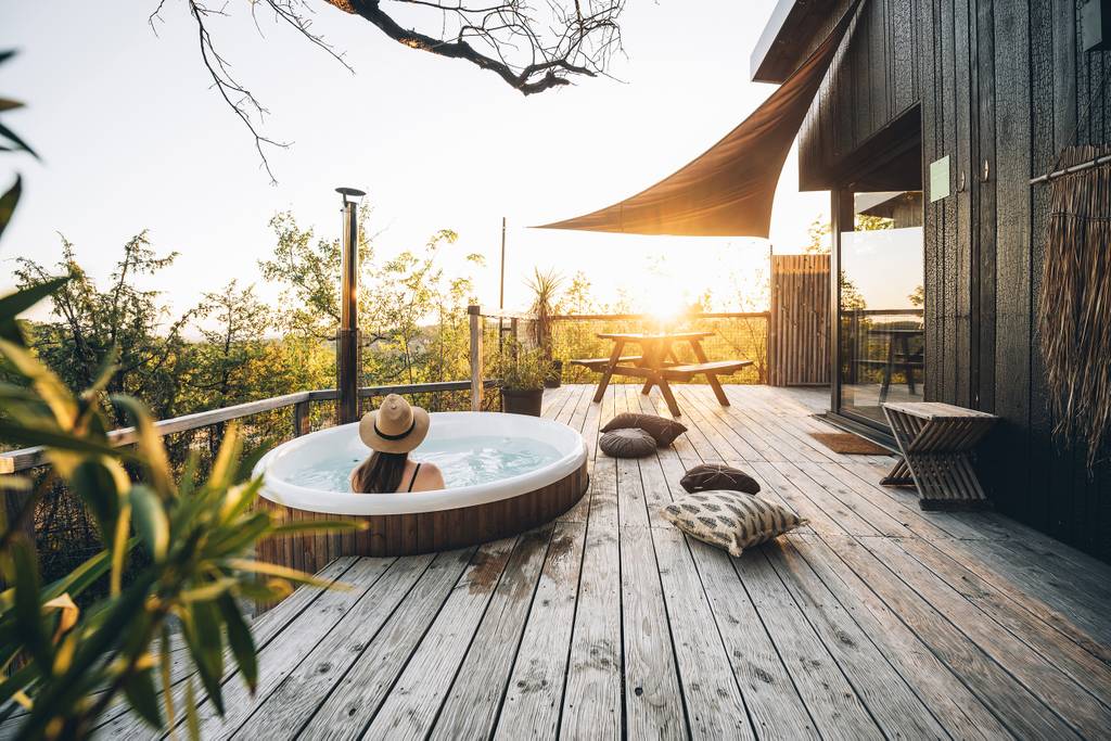 Vrouw zit een hot tub bij een landelijk gelegen huisje
