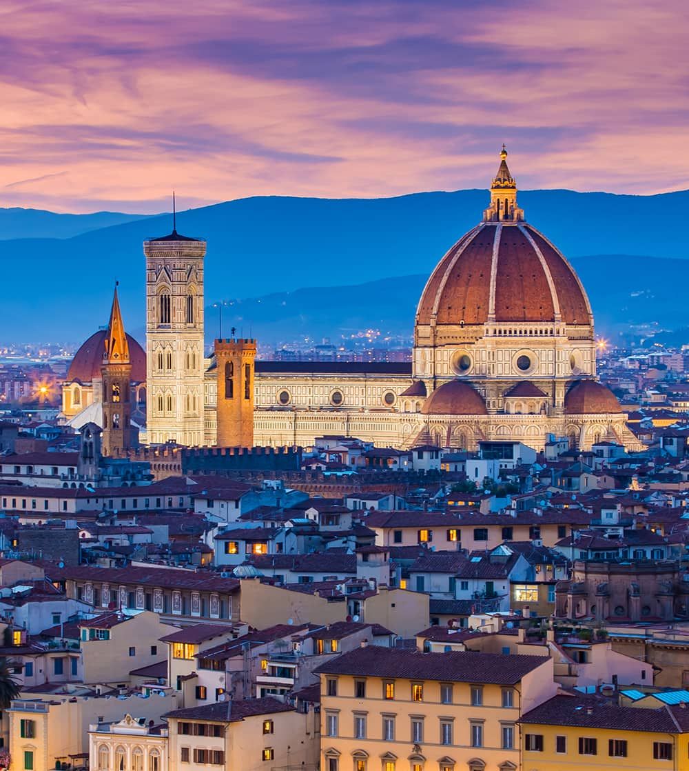 Aerial view of a city with a large red-domed building in the middle of the city at sunset