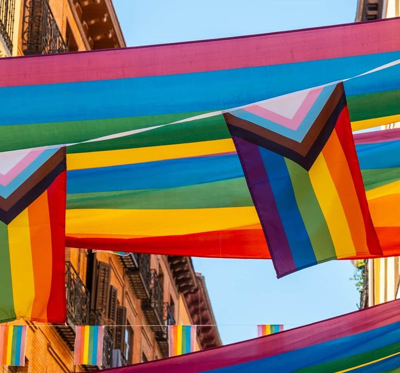 Rainbow flags and banners hanging above a street on a sunny day