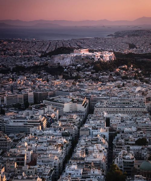 Aerial view of a city at sunset with ancient ruins on a hill in the center