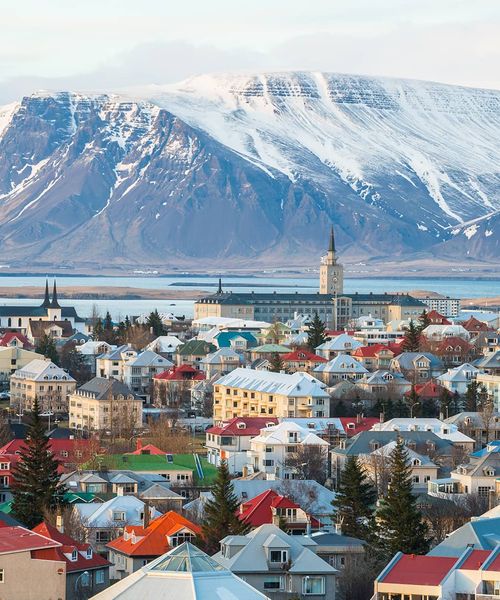 Aerial view of a colorful small city with snowy mountains in the background