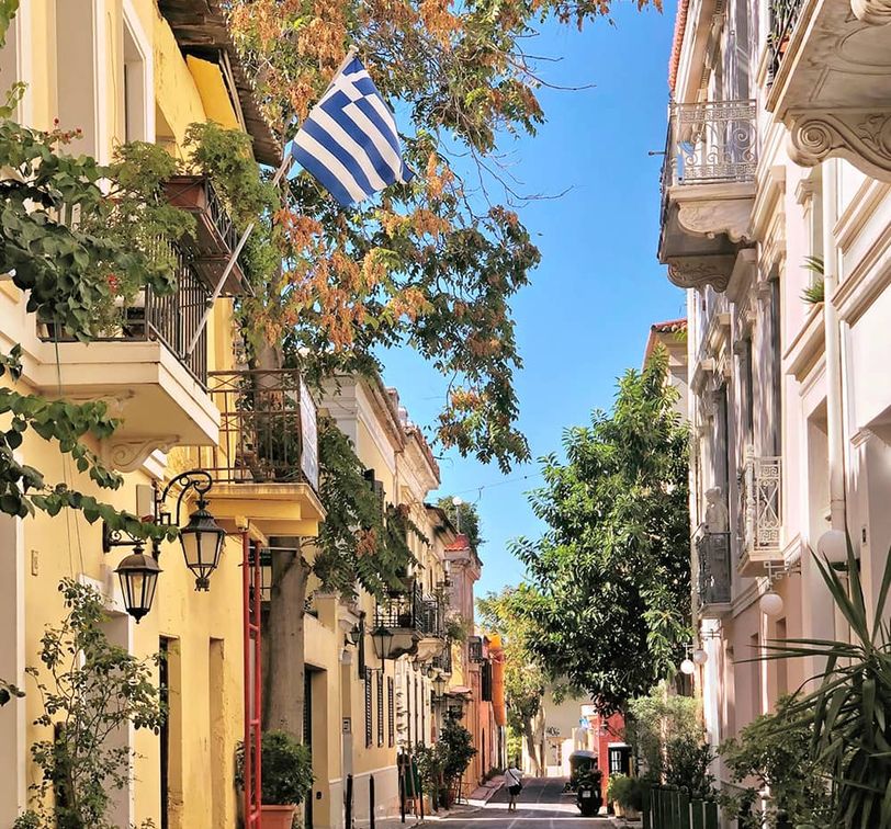 A street with a Greek flag hanging from a balcony