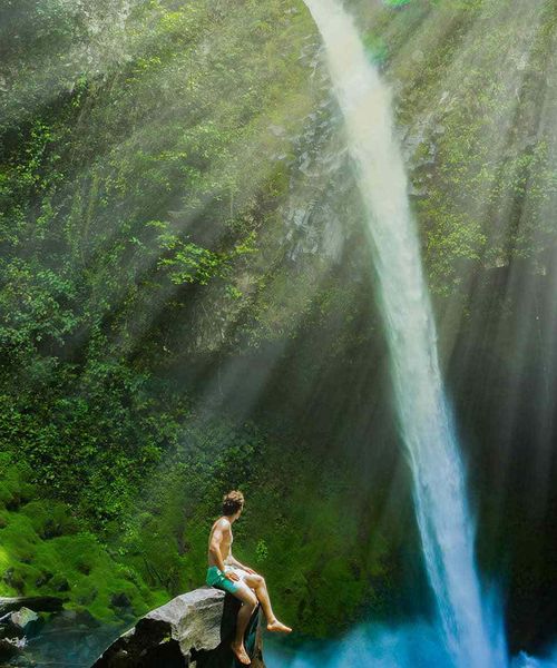 A man sitting on a rock overlooking a waterfall