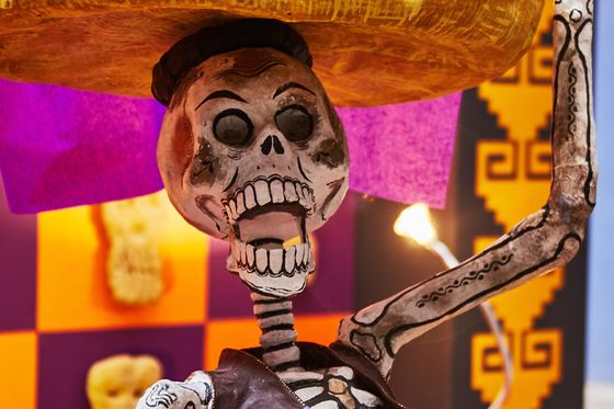 A skeleton figure holding a tray of food on their head