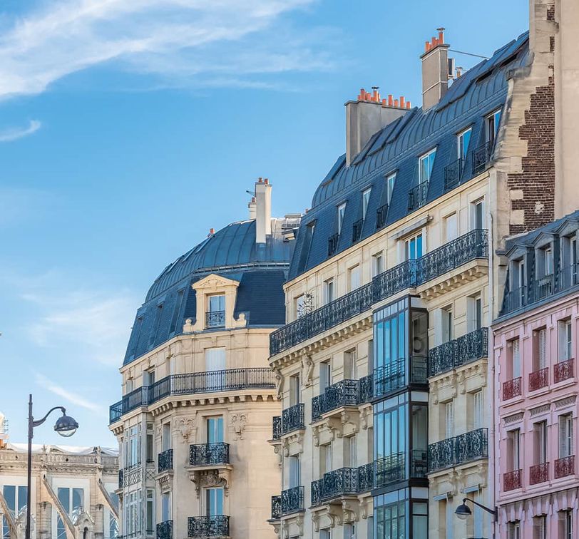 A row of differently colored ornate buildings with many stories and many windows