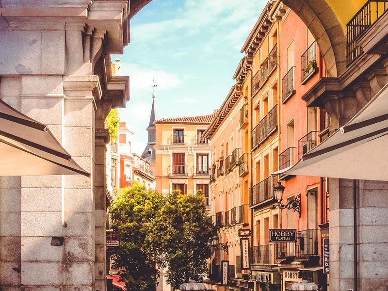 A city street lined with buildings framed by a large stone arc