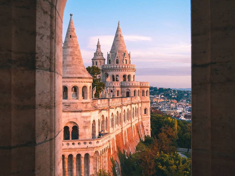 A view of a grand castle during sunset from behind a curved dome window opening
