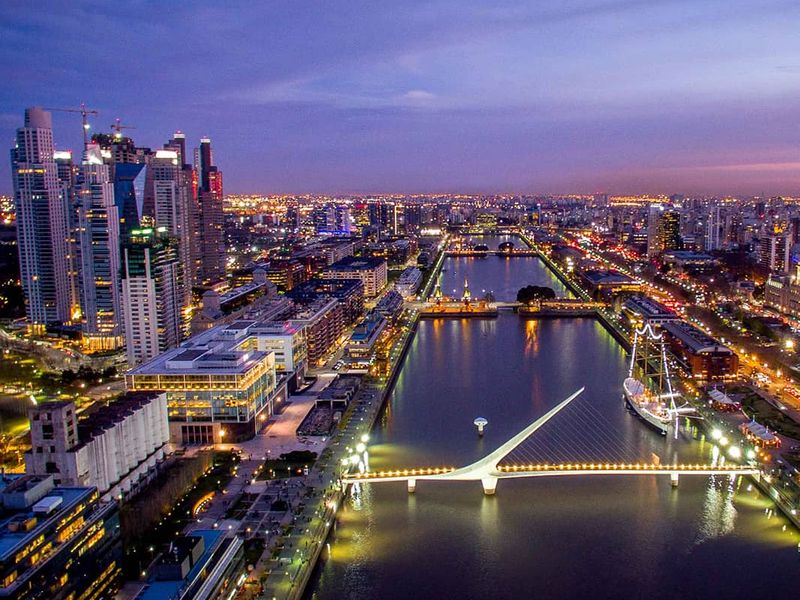 An aerial view of a large bustling city during sunset with a waterway running through the middle of the city