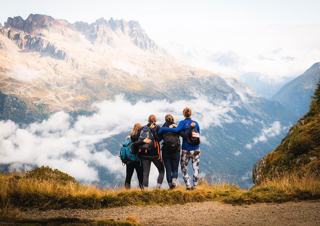 Four girls hugging at the top of a mountain looking into the distance.