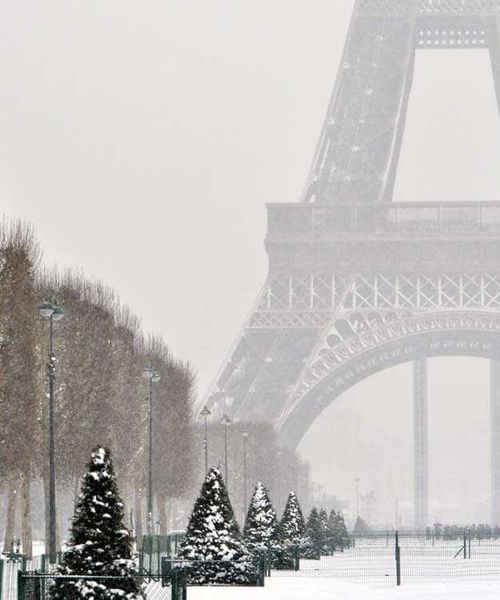 A snow covered plaza leading to a massive metal tower