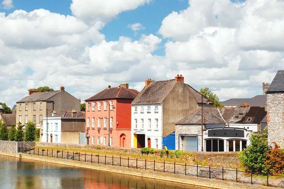 A row of stone buildings along a river on a sunny day