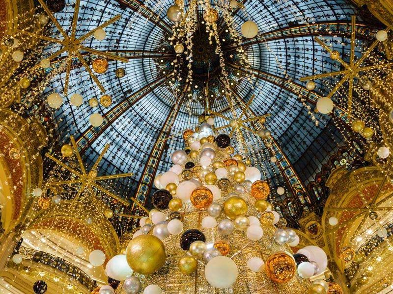 Inside of a domed ceiling decorated with yellow string lights and white and gold balloons